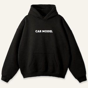 May include: Black hoodie with a hood and a front pocket. The words "CAR MODEL" are printed in white block letters across the chest. The sweatshirt has long sleeves and a relaxed fit.