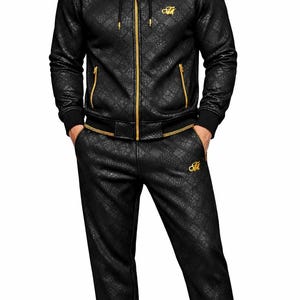 Puede incluir: Ch&aacute;ndal negro con estampado de piel de reptil. La chaqueta tiene capucha, cremallera dorada y detalles dorados en los hombros. El pantal&oacute;n a juego tiene cintura con cord&oacute;n. Un logo "M" dorado est&aacute; presente.