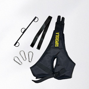 May include: Black exercise harness with the word "SUPERSILA" in yellow. The harness has adjustable straps and a buckle. Included are three silver carabiner clips, a black metal bar with three rings, and two black straps.