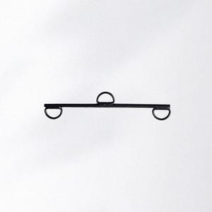 May include: A black metal bar with three D-shaped loops. The loops are evenly spaced along the bar, with one in the center and one at each end. The object is set against a white background.