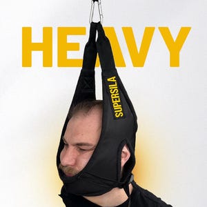 May include: A black neck harness for exercise featuring the text SUPERSILA in yellow on the side strap. The harness is suspended by a metal carabiner and a black strap. The word HEAVY is displayed in large yellow letters in the background.