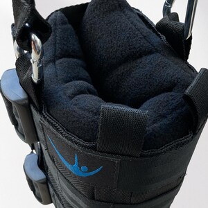 May include: Black inversion boots with a padded interior and adjustable straps. The boots have a blue logo and are designed to hang from a bar for inversion therapy. The boots are made of durable materials and feature metal carabiner clips.
