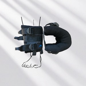 May include: Black ankle and foot brace with adjustable straps and buckles. The brace has a padded section for the ankle and a blue logo. The brace is designed to provide support and stability.