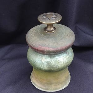 May include: A green, yellow, and brown ceramic jar with a brass lid featuring a five-pointed star.