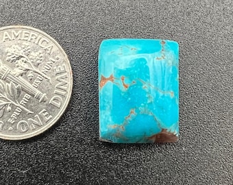 Puede incluir: Un cabujón turquesa con matriz marrón. La piedra es rectangular y mide aproximadamente 2,5 cm por 3,8 cm.
