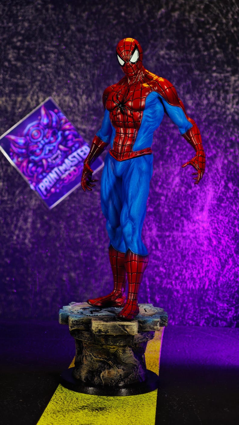 Puede incluir: Figura detallada de Spider-Man en una pose din&aacute;mica, luciendo su ic&oacute;nico traje rojo y azul. La figura se encuentra sobre una base texturizada, con un fondo p&uacute;rpura. Un letrero con el texto "PRINTMASTER 300" es visible.