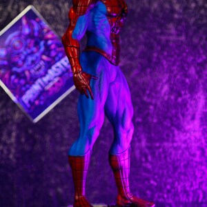Puede incluir: Una figura detallada de Spider-Man en una pose cl&aacute;sica, con un traje rojo y azul. La figura est&aacute; sobre una base de piedra. Un letrero con el texto "PRINTMASTER" est&aacute; en el fondo.