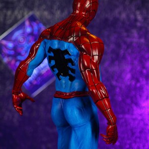 Puede incluir: Una detallada figura de Spider-Man, vista desde atr&aacute;s. La figura est&aacute; en una pose din&aacute;mica, mostrando el ic&oacute;nico traje rojo y azul del personaje. Las secciones rojas incluyen la cabeza, los hombros y los brazos, mientras que el torso y las piernas son azules.