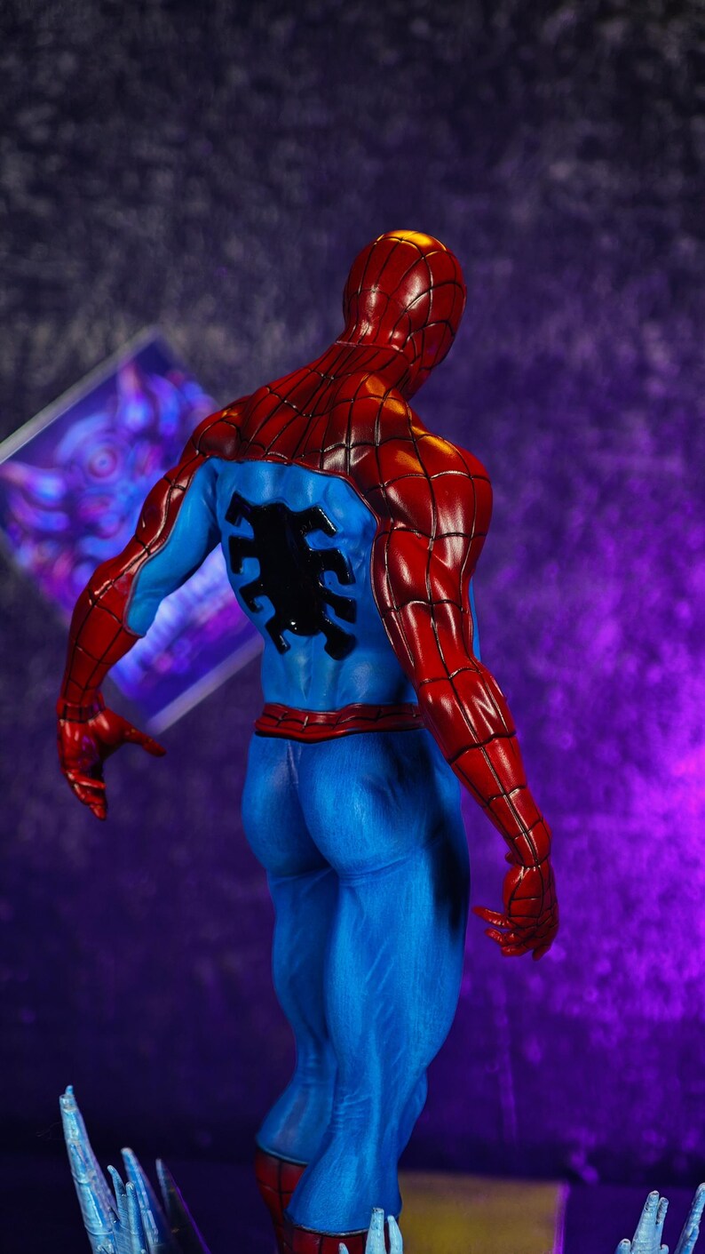 Puede incluir: Una detallada figura de Spider-Man, vista desde atr&aacute;s. La figura est&aacute; en una pose din&aacute;mica, mostrando el ic&oacute;nico traje rojo y azul del personaje. Las secciones rojas incluyen la cabeza, los hombros y los brazos, mientras que el torso y las piernas son azules.