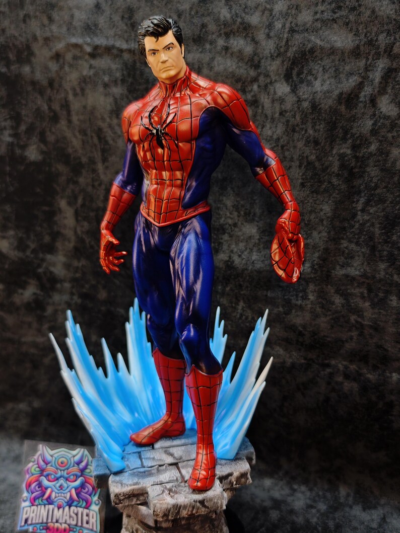 Op de afbeelding: Een gedetailleerd beeldje van Spider-Man in een dynamische pose, met zijn iconische rood-blauwe pak. Het beeld staat op een voetstuk met blauwe waterachtige accenten. Het beeld heeft een zwart spinnenembleem op de borst.