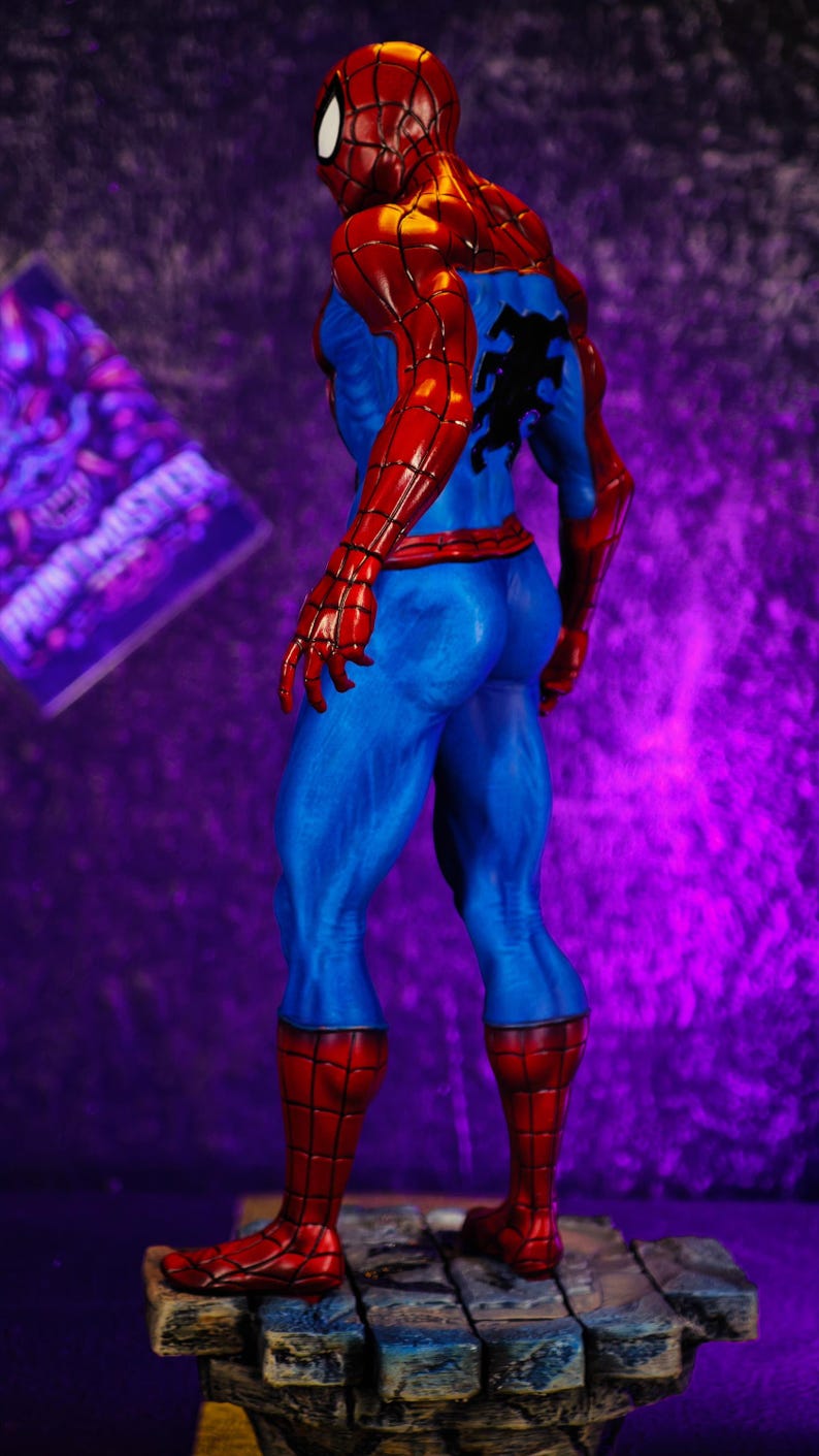 Puede incluir: Figura detallada de Spider-Man, vista desde atr&aacute;s, mostrando su ic&oacute;nico traje rojo y azul. La figura se encuentra sobre una base texturizada con un fondo p&uacute;rpura. El disfraz presenta un emblema de ara&ntilde;a negra en la espalda.
