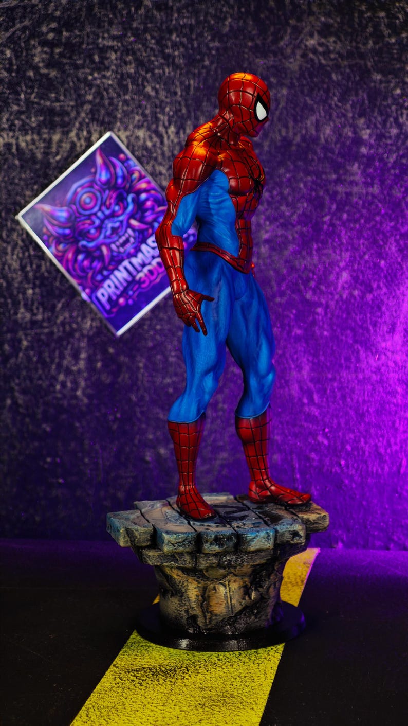 Puede incluir: Una figura detallada de Spider-Man en una pose cl&aacute;sica, con un traje rojo y azul. La figura est&aacute; sobre una base de piedra. El fondo es un degradado de p&uacute;rpura y negro. Un letrero con el texto "PRINTMAS 300" est&aacute; en el fondo.