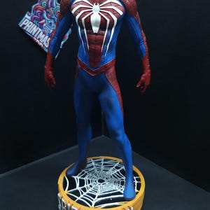 May include: A red and blue Spider-Man action figure stands on a round base with a white spider web design. The base is labeled "SPIDER-MAN".