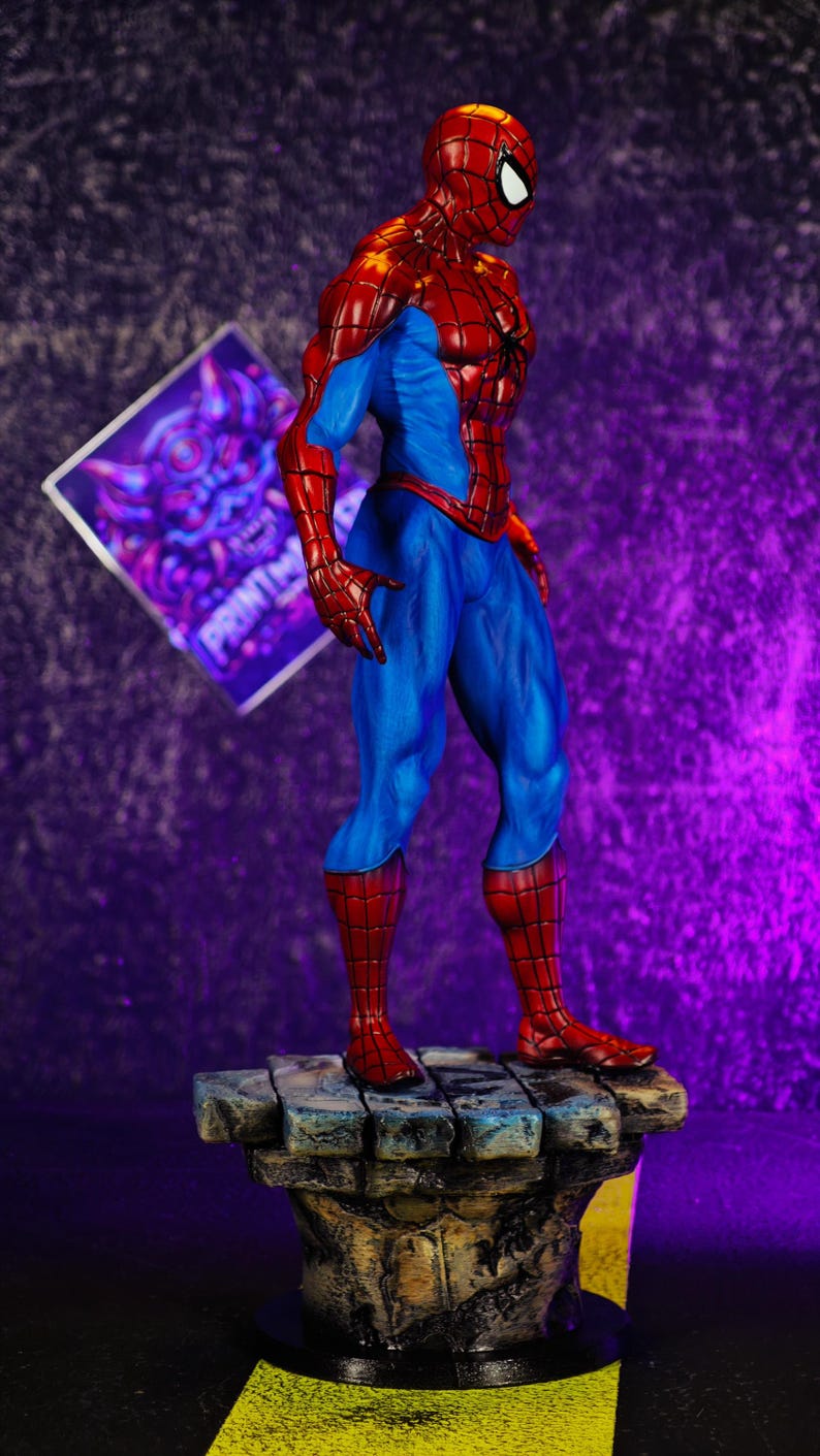 Puede incluir: Una detallada figura de Spider-Man en una pose din&aacute;mica, mostrando su ic&oacute;nico traje rojo y azul. La figura se encuentra sobre una base texturizada, similar a la piedra. El fondo es un degradado de p&uacute;rpura y negro.