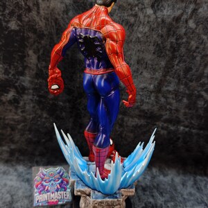 Op de afbeelding: Een gedetailleerd beeld van Spider-Man, van achteren gezien, met zijn iconische rood-blauwe pak. De figuur is dynamisch geposeerd en staat op een basis met waterachtige effecten. Het beeld heeft een gedetailleerd gespierd lichaam en is een verzamelobject.