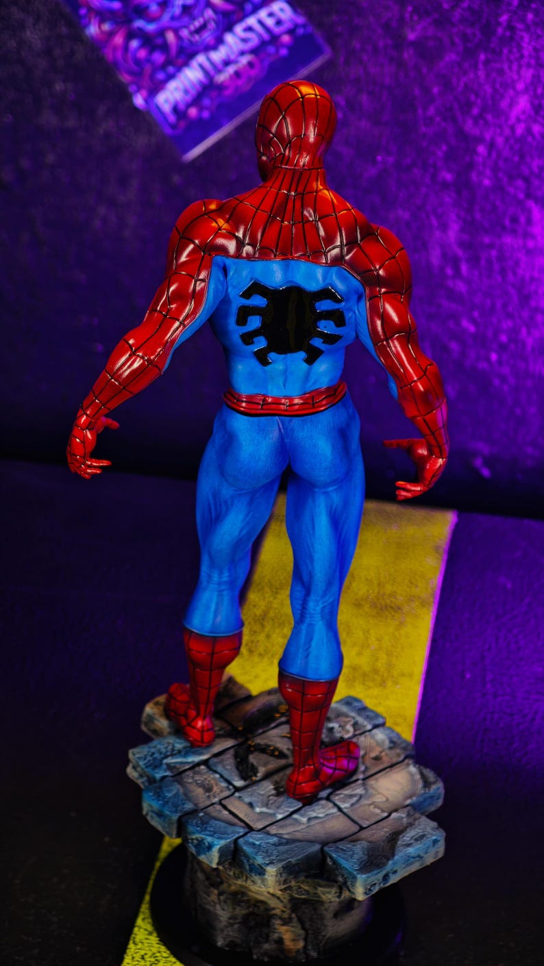 Puede incluir: Figura de acci&oacute;n de Spider-Man, vista desde atr&aacute;s, con un traje azul y rojo. La figura est&aacute; sobre una base detallada, con forma de piedra. El dise&ntilde;o y la pose de la figura son muy detallados.