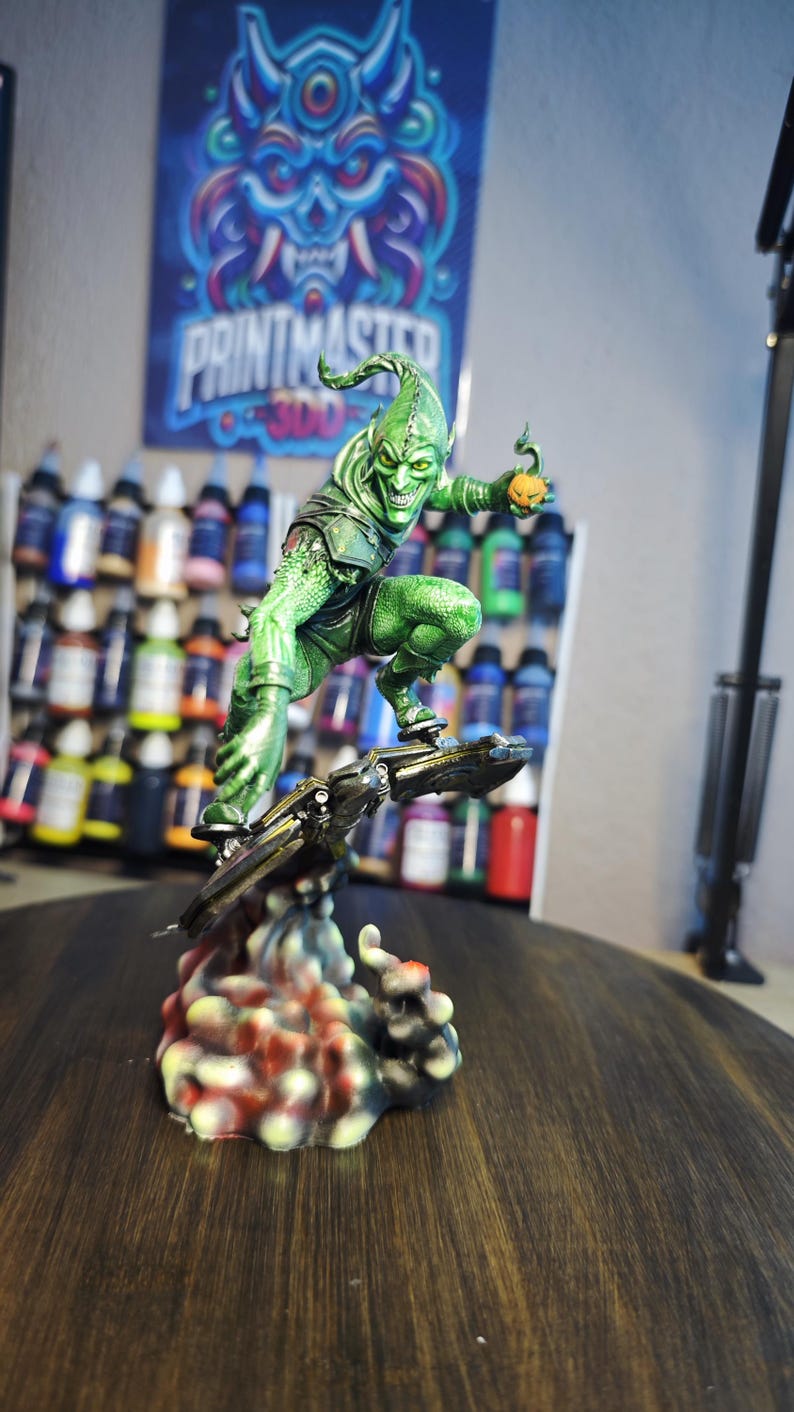 Puede incluir: Una detallada figura del Duende Verde, un villano de c&oacute;mic, montado en un planeador. La figura es predominantemente verde con una bomba de calabaza en la mano. La base es un dise&ntilde;o abstracto y colorido. Un p&oacute;ster con el texto "PRINTMASTER 300" est&aacute; en el fondo.