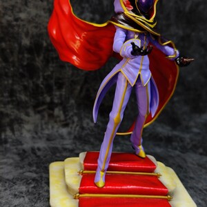 Pu&ograve; includere: Statuetta dettagliata di un personaggio in abito viola con finiture dorate, mantello rosso e casco nero. La figura &egrave; su una piattaforma tappezzata di rosso con dettagli dorati. Il mantello fluttua.