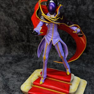 Pu&ograve; includere: Statuetta dettagliata di un personaggio in abito viola con dettagli dorati, mantello nero e rosso e casco. La figura &egrave; su una piattaforma con tappeto rosso e bordi dorati.