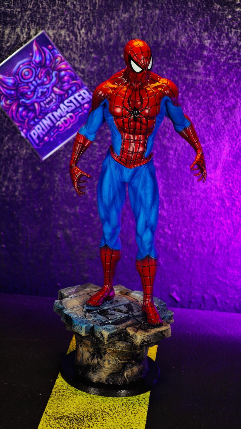 Puede incluir: Una detallada figura de Spider-Man con su cl&aacute;sico traje rojo y azul, de pie sobre una base rocosa. La figura tiene una pose din&aacute;mica, con un dise&ntilde;o de telara&ntilde;a en el pecho. Un letrero morado con el texto "PRINTMASTER 3DD" est&aacute; en el fondo.