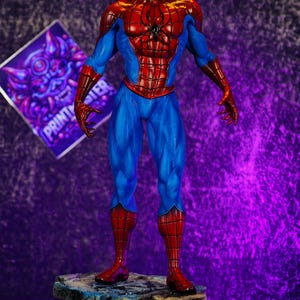 Puede incluir: Figura detallada de Spider-Man con su cl&aacute;sico traje rojo y azul, de pie sobre una base texturizada. La figura tiene una pose din&aacute;mica con los brazos extendidos. El fondo es un degradado de tonos p&uacute;rpuras.