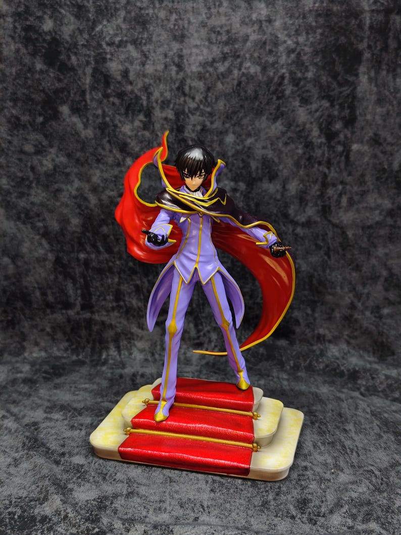 Pu&ograve; includere: Statuetta dettagliata di un personaggio in un completo viola e oro con un mantello rosso fluente. La figura &egrave; su una piattaforma con tappeto rosso con dettagli dorati. Il personaggio ha i capelli neri ed &egrave; in posa dinamica.