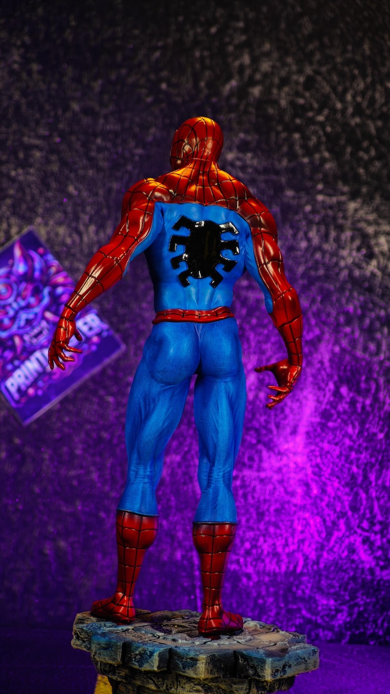 Puede incluir: Figura detallada de Spider-Man, vista desde atr&aacute;s. La figura lleva un cl&aacute;sico traje rojo y azul con un emblema de ara&ntilde;a negro en la espalda. La figura est&aacute; sobre una base de piedra.