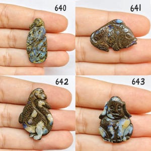 Op de afbeelding: Vier gebeeldhouwde edelsteenbeeldjes. De beeldjes zijn bruin met blauwe en gele accenten. De beeldjes zijn genummerd 640, 641, 642 en 643. De beeldjes worden in een hand gehouden.