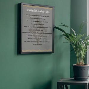 Può includere: Una stampa incorniciata con il testo "Karakia mō te Ata" in un carattere stilizzato. Il testo è in una lingua straniera, con un bordo dorato e grigio. La cornice è nera e la stampa è appesa a una parete verde.