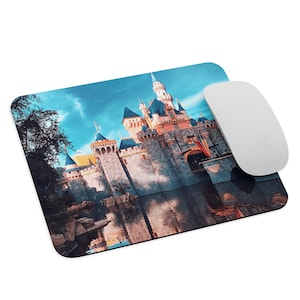 May include: A blue and pink castle with a reflection in the water. The castle is surrounded by trees and a blue sky with white clouds.