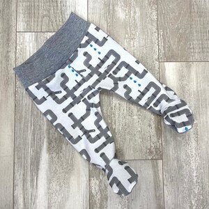 May include: Gray and white baby leggings with a pattern of pipes and water drops. The leggings have a gray waistband.