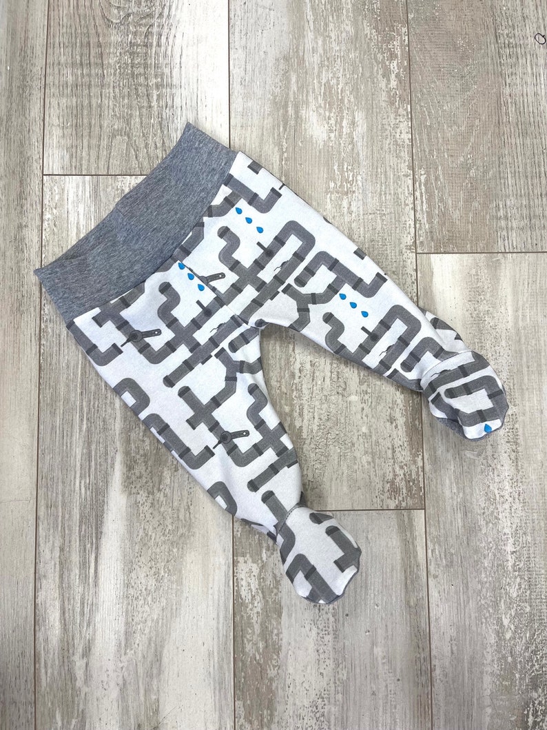May include: Gray and white baby leggings with a pattern of pipes and water drops. The leggings have a gray waistband.