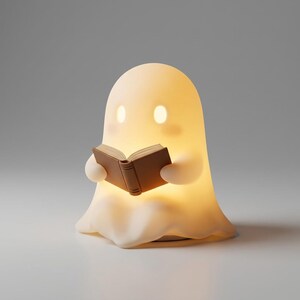 May include: A glowing, off-white, ghost-shaped lamp with a smooth, rounded form. The ghost has two oval-shaped illuminated eyes and is holding a small, solid brown book open in its hands. The lamp emits a soft, warm light from within its body.
