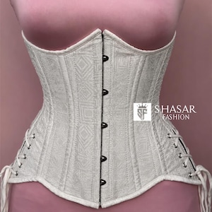 May include: A white corset featuring a subtle geometric jacquard pattern, a front busk closure with silver-toned metal clasps, and side lacing with white cords. The garment displays the text SHASAR FASHION with a crown logo on the right side.