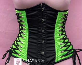 Peut inclure: Un corset noir et vert néon doté d'une fermeture à busc sur le devant avec des agrafes en métal argenté. Les côtés présentent des panneaux vert néon et un laçage noir à travers des œillets argentés. Le texte SHASAR FASHION est imprimé devant.