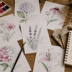Puede incluir: Impresiones art&iacute;sticas florales en acuarela con varias flores, como una peon&iacute;a, lavanda y lirio. Las impresiones est&aacute;n sobre papel blanco, con pinturas de acuarela y un cuaderno de bocetos cerca. La paleta de colores incluye rosa, morado y verde.