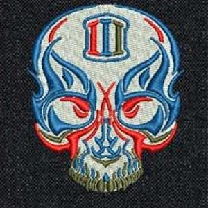 May include: Embroidered skull patch with a tribal design in blue, red, and green on a light background. The skull features the Roman numeral "III" at the top. The patch is set against a dark, textured background.