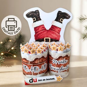 May include: A DIY advent calendar craft featuring a cutout of Santa's legs in black boots and red pants emerging from two cylindrical chimney containers. The containers are decorated with brick patterns, the text HO, HO, HO, and 24 süße Kleinigkeiten.