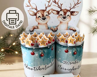 Puede incluir: Un set de calendario de adviento DIY con dos recipientes cilíndricos que muestran una escena invernal de dos ciervos. Los recipientes contienen tubos con estrellas numeradas del 1 al 24. El texto dice Adventskalender, 24 süße Kleinigkeiten y du bist ein Geschenk.
