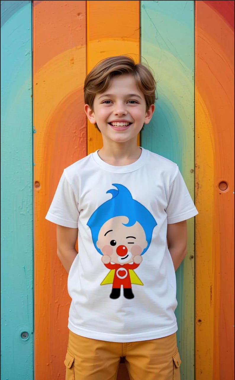 Może przedstawiać: Biały t-shirt z kr&oacute;tkim rękawem z nadrukiem graficznym przedstawiającym postać z kresk&oacute;wki z niebieskimi włosami, czerwonym nosem oraz w czerwonym stroju z ż&oacute;łtą peleryną. Postać mruga okiem i trzyma dłonie uniesione blisko twarzy na środku.