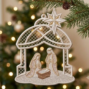 Könnte beinhalten: Ein weiß-goldener, bestickter Weihnachtsanhänger mit einer Krippenszene und einem Stern an der Spitze. Das Design zeigt zwei Figuren, die über einer Krippe in einem bogenförmigen Rahmen mit Gittermuster stehen, alles aus Garn gefertigt.