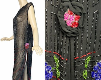 May include: A sleeveless black sheer dress featuring vertical rows of black beads, red beaded accents, and floral motifs. The dress includes a large fabric rose appliqué with pink and red beads, and a high side slit along the lower portion of the garment.