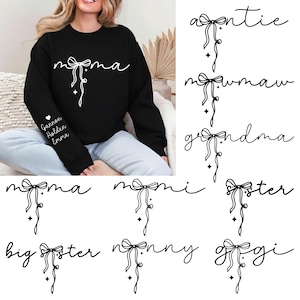 Puede incluir: Sudadera negra con la palabra "mama" en escritura blanca, con un diseño de lazo. La manga izquierda tiene los nombres: Gannon, Holden y Emma. Diseños adicionales incluyen "auntie", "mawmaw", "grandma", "momma", "moni", "sister", "big sister", "nanny" y "gigi".