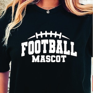 May include: Black t-shirt with the words "FOOTBALL MASCOT" in bold white letters. Above the text is a white football graphic. The shirt is a crew neck style.