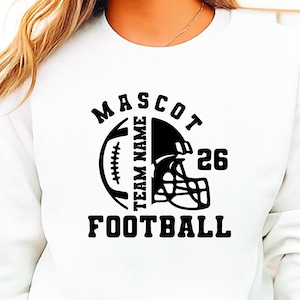 May include: White sweatshirt with a black football-themed graphic. The design includes a football, helmet, the word "MASCOT", "TEAM NAME", the number "26", and the word "FOOTBALL". The sweatshirt is a casual garment.