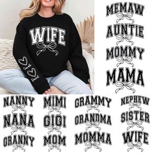Pode incluir: Camisola preta com a palavra "WIFE" em letras brancas e um laço. A manga esquerda tem dois corações com os nomes "Sarah" e "David". Designs adicionais incluem "MEMAW", "AUNTIE", "MOMMY", "MAMA", "NANNY", "MIMI", "GRAMMY", "NEPHEW", "NANA", "GIGI", "GRANDMA", "SISTER", "GRANNY", "MOM", "MOMMA" e "WIFE".