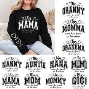 Op de afbeelding: Zwart sweatshirt met de witte tekst "This Mama wears her heart on her sleeve". De linkermouw heeft twee harten met de namen "Sarah" en "David". Andere ontwerpen zijn "Granny", "Momma", "Grandma", "Nanny", "Auntie", "Nana", "Mimi", "Mom", "Mommy" en "Gigi".