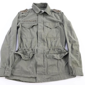 May include: Olive green military-style jacket with a collared neckline, two chest pockets, and two lower pockets. The jacket features decorative studs on the shoulders and chest. The waist has an adjustable drawstring.