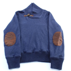 May include: A navy blue sweater with brown leather elbow patches. The sweater has a ribbed hem and cuffs, a high collar, and a leather closure at the neckline. A classic, casual style.