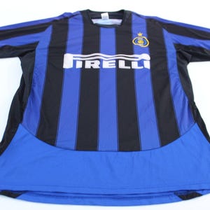 May include: A blue and black striped soccer jersey with the word "IRELLI" in white across the chest. The jersey has a blue lower section and a team logo on the upper chest.